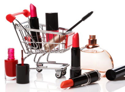 Shopping trolley with make-up products over white background